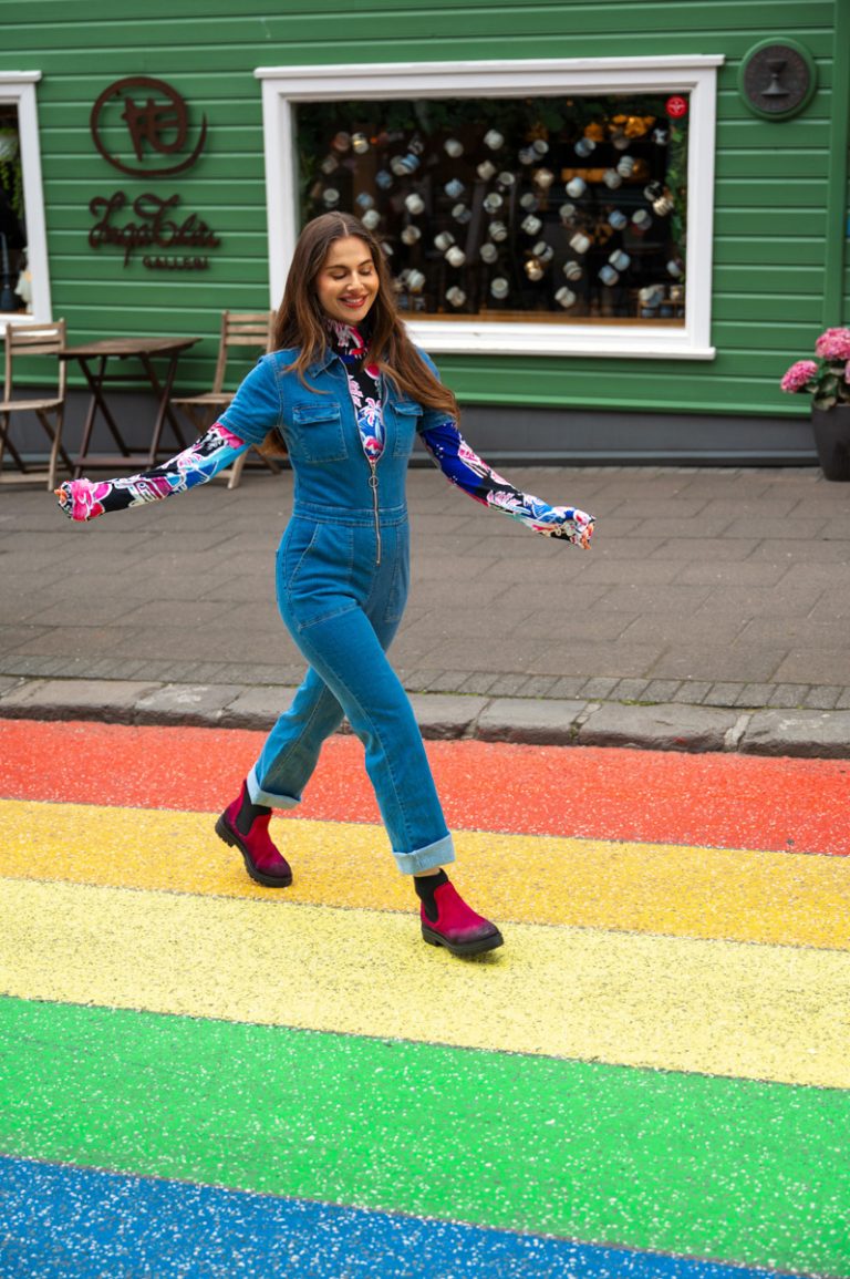 Lachend model loopt over een regenboogzebrapad met gekleurde winter laarzen van Nederlandse schoenenmerk Lazamani.