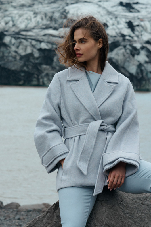 Luxe winterjas van kledingmerk OSCAR the Collection, gefotografeerd in IJsland voor een gletscher.
